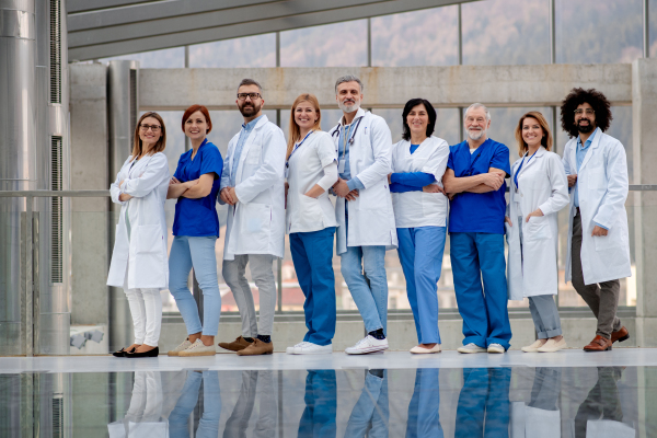 Portrait of team of doctors, full length with reflection. Healthcare team with doctors, nurses, professionals in medical uniforms in hospital, modern clinic.