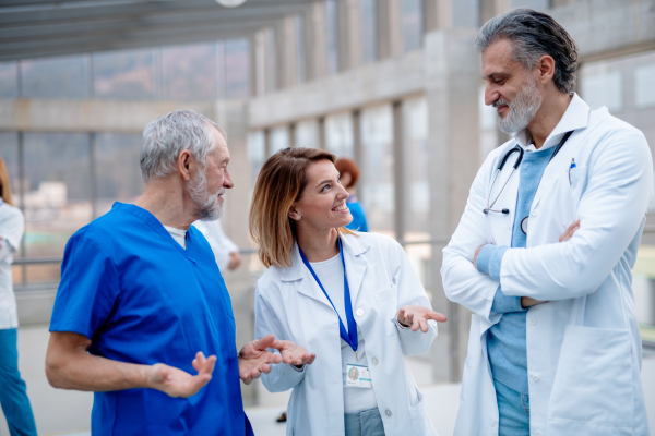 Group of doctors talking during conference, discussing research findings. Medical networking. Medical experts attending an education event, seminar in board room. Age and gender equity in healthcare.