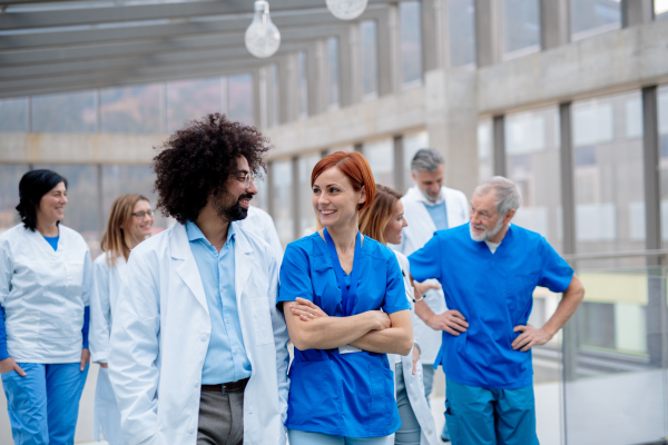 Team of doctors discussing unique surgery success, walking across corridor. Colleagues, doctors team discussing patients diagnosis. in modern hospital, clinic.