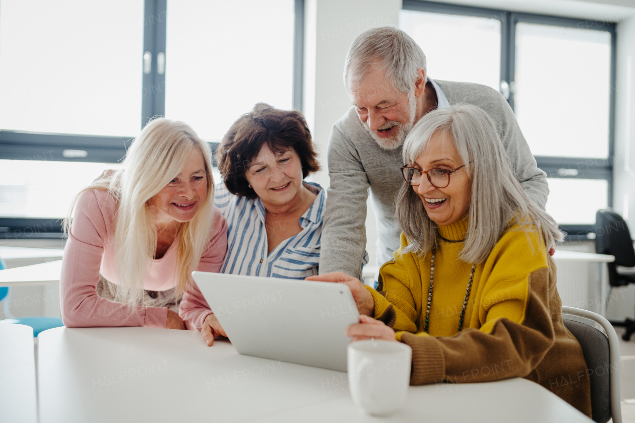 Group of senior students looking at tablet screen, learning new skill. Elderly people attending computer and technology education class.