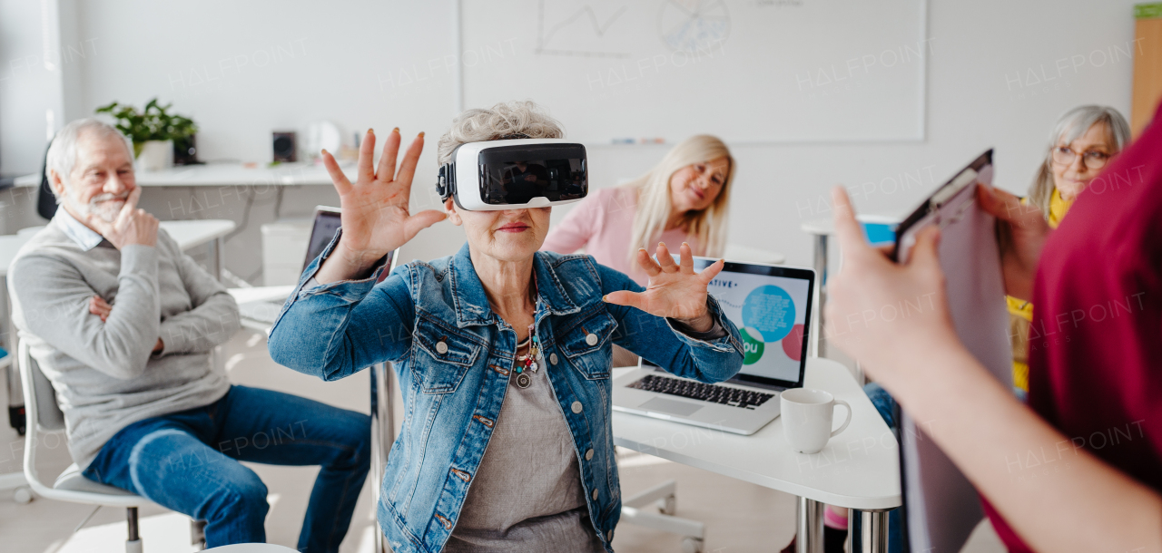 Group of seniors with VR goggles on computer and technology education class. Elderly people learning about virtual reality, using VR headset