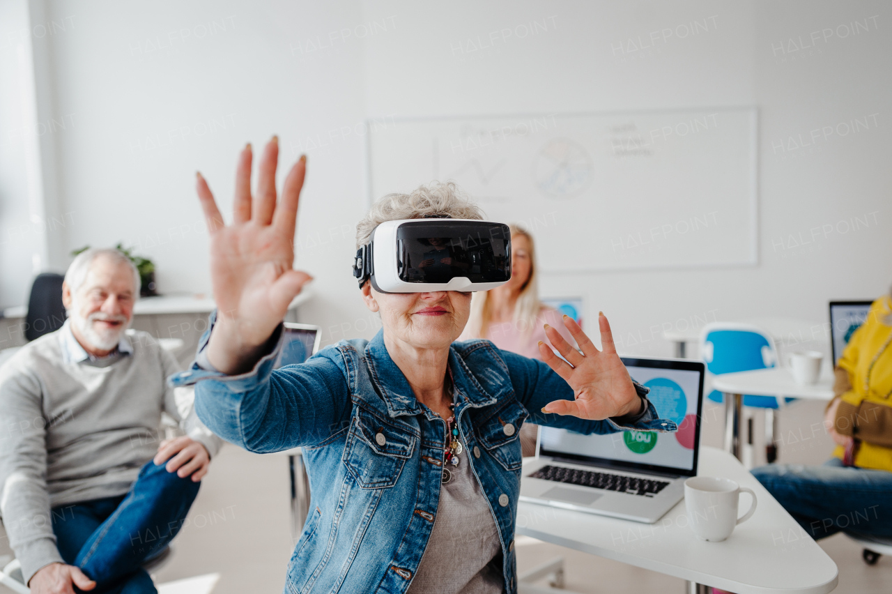 Group of seniors with VR goggles on computer and technology education class. Elderly people learning about virtual reality, using VR headset