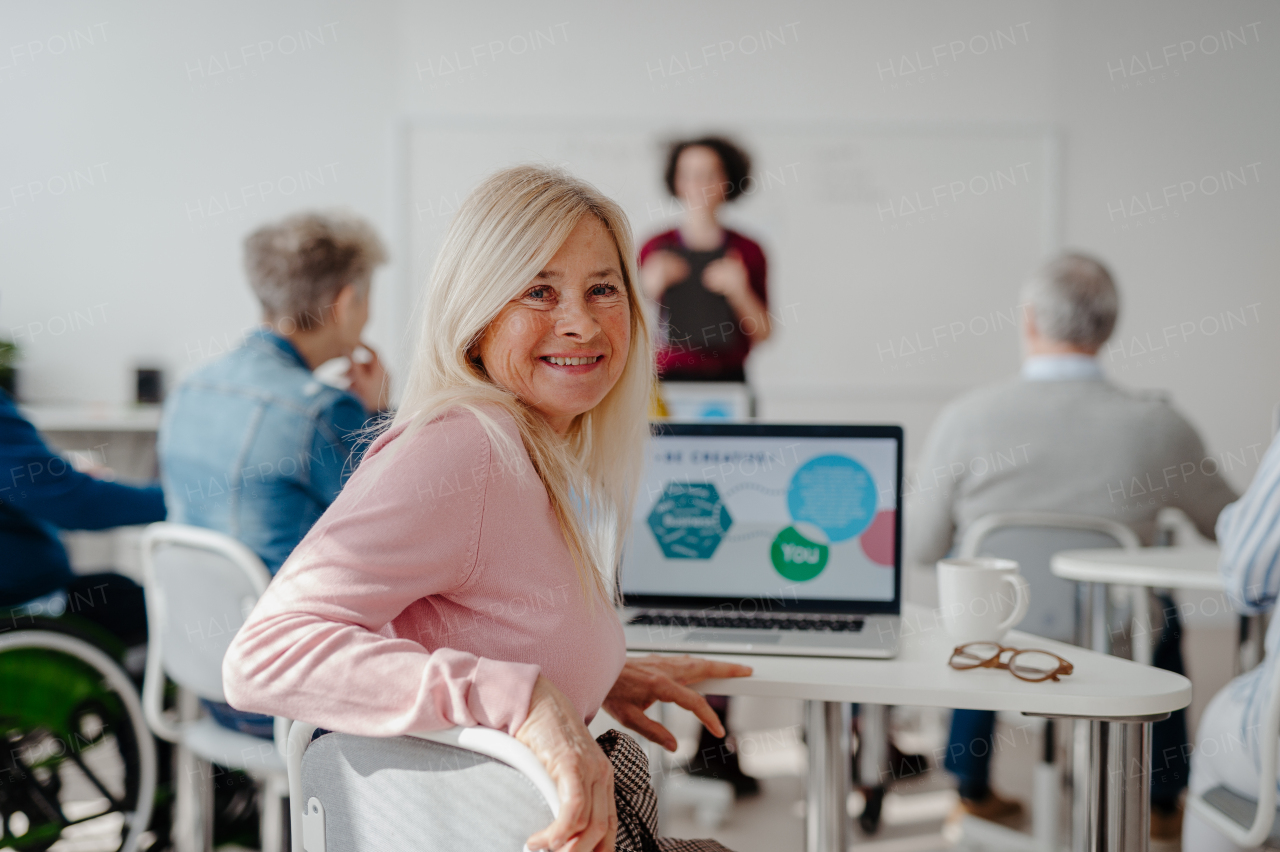 Portrait of female senior student learning how to work with digital technology. Elderly people attending computer and technology education class.