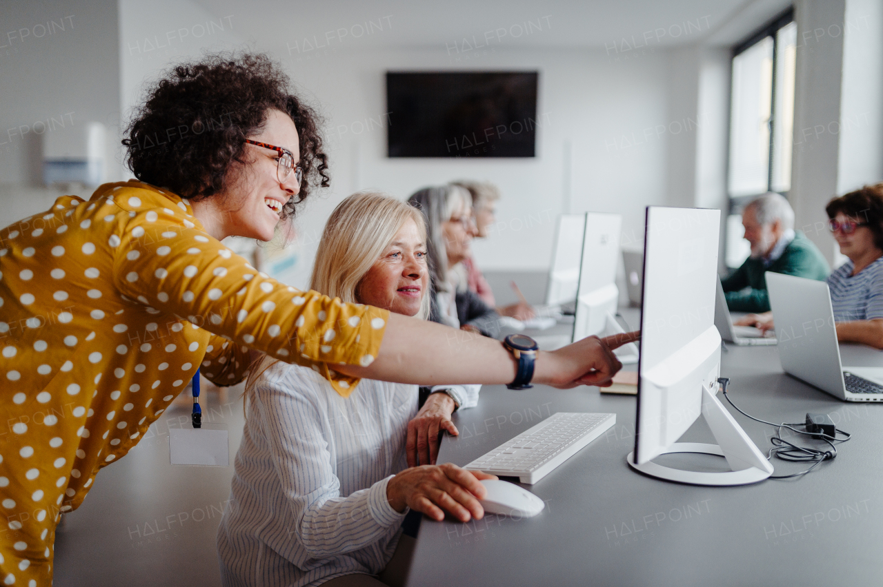 Portrait of female senior student learning how to work with digital technology. Elderly people attending computer and technology education class.