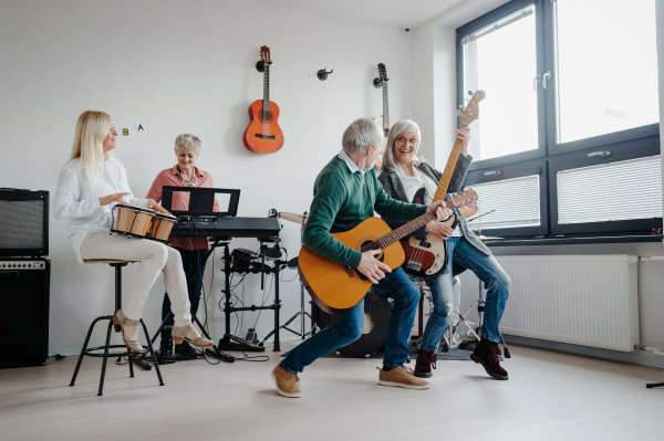 Group of seniors meeting to play musical instruments together in band. Therapeutic effect of music for elderly people.