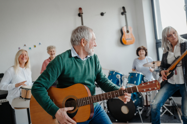 Group of seniors meeting to play musical instruments together in band. Therapeutic effect of music for elderly people.