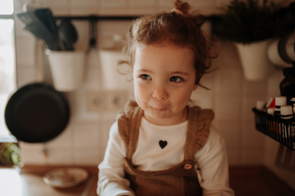 Portrait of an adorable little girl sitting on kitchen counter.