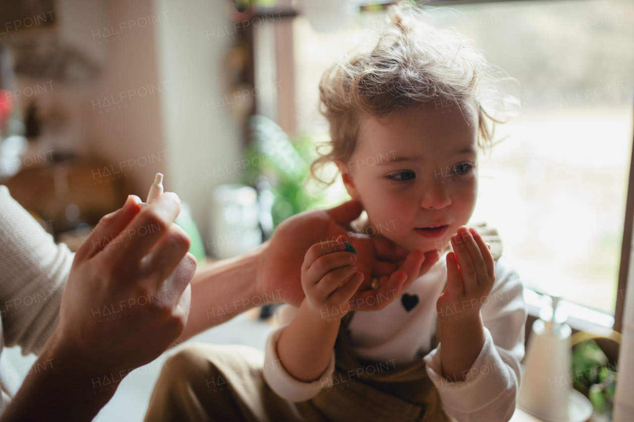 Sick girl with cold at home has stuffy nose. Father helping little daughter, using nasal spray in his nose