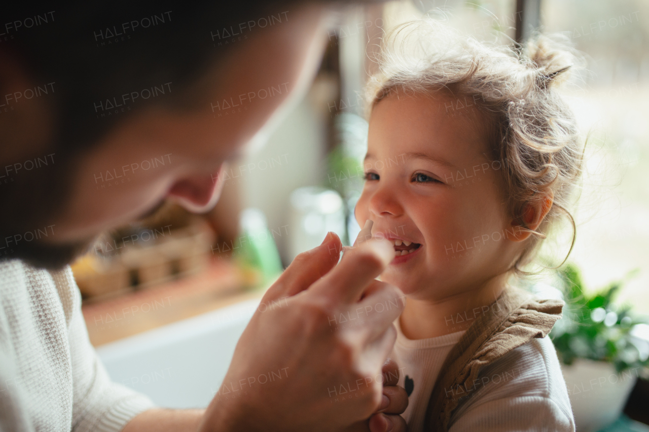 Sick girl with cold at home has stuffy nose. Father helping little daughter, using nasal spray in his nose