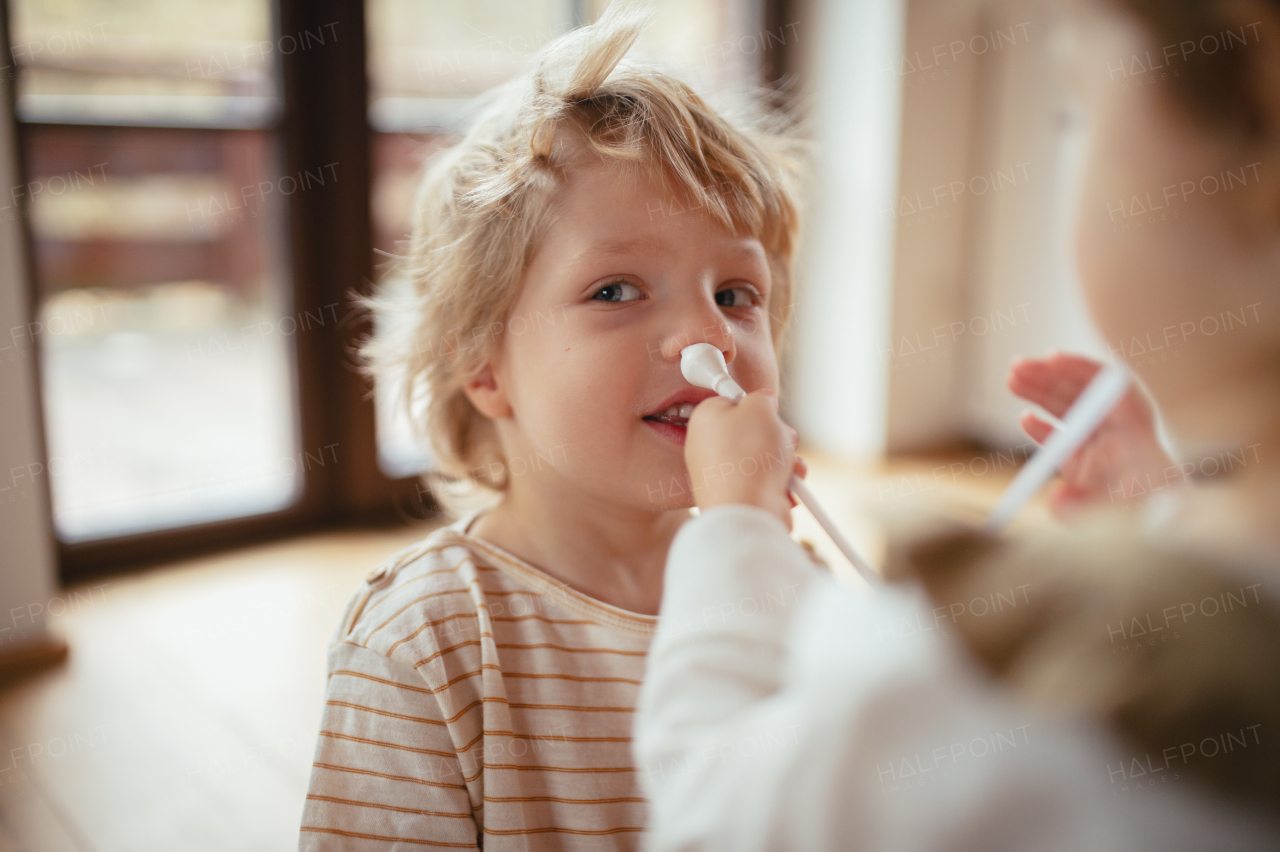 Boy with stuffy nose, using nasal suction bulb to clear mucus from his nose