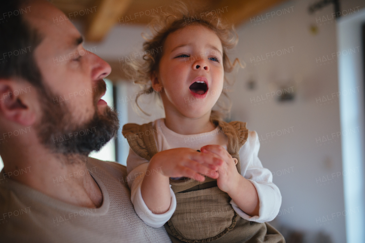 Sick girl with fever and cold at home. Father holding crying daughter