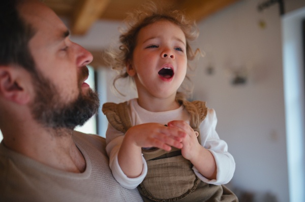 Sick girl with fever and cold at home. Father holding crying daughter