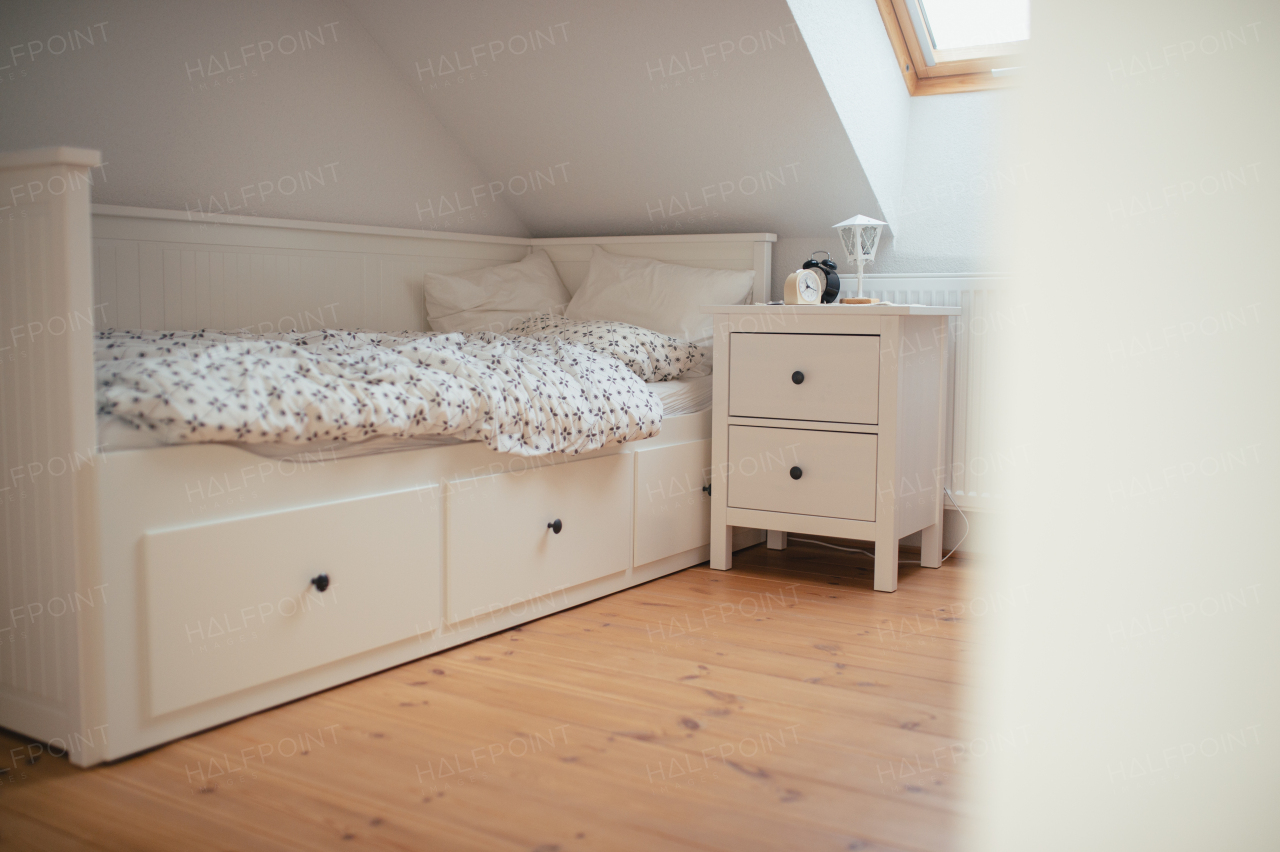 Simple modern bedroom in the attic with wooden furniture and floors.