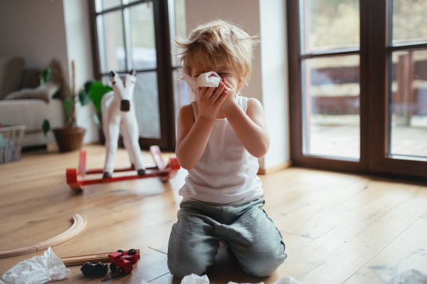 Sick boy with cold has stuffy nose and blowing his nose