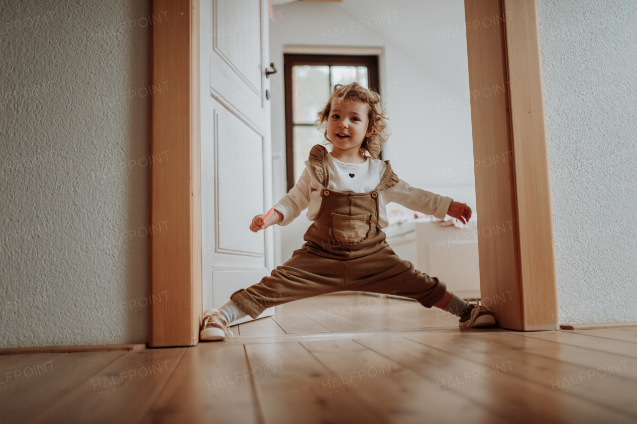 Portrait of an adorable little girl spreading her legs between door frame