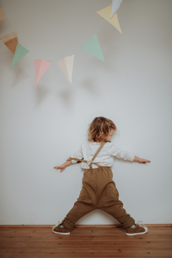 Portrait of an adorable little girl standing under paper garland