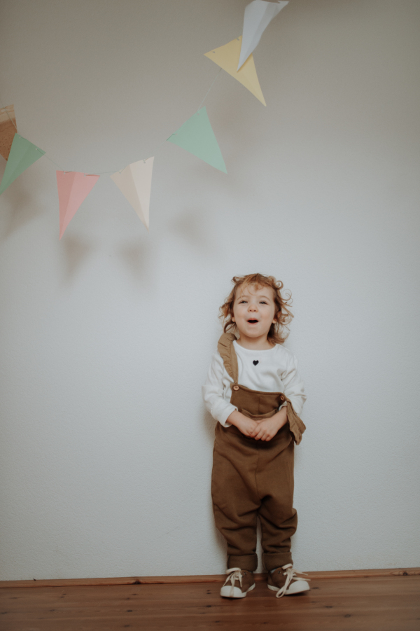 Portrait of an adorable little girl standing under paper garland