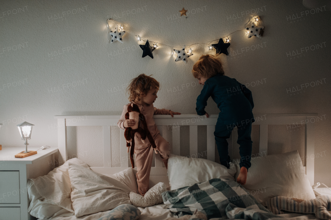 Candid portrait of siblings playing together in bed laughing, having fun