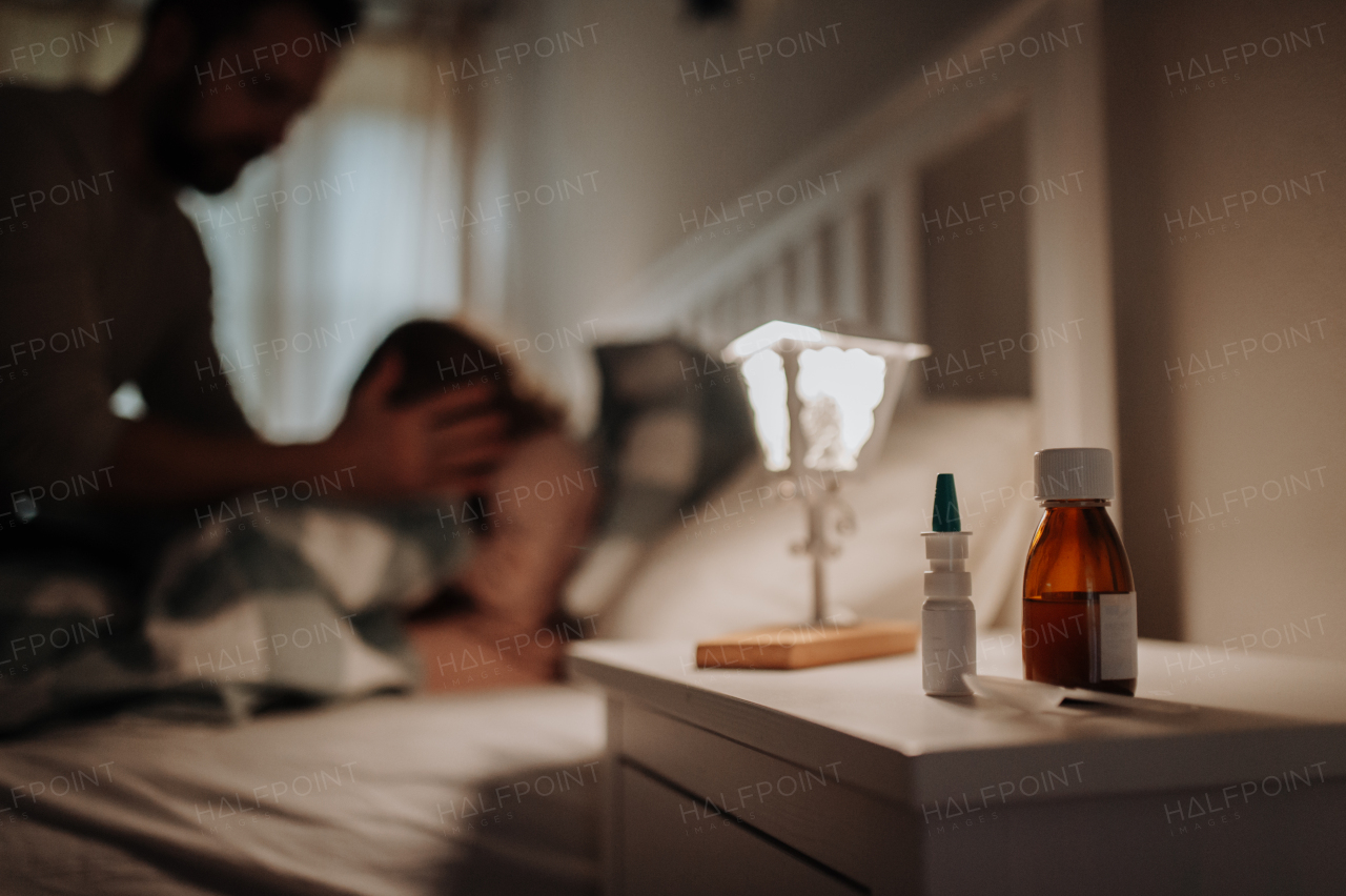 Close up on medication on bedside table. Sick girl with cold lying in the bed