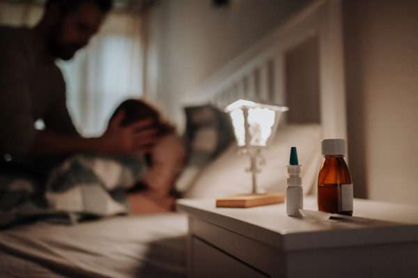 Close up on medication on bedside table. Sick girl with cold lying in the bed