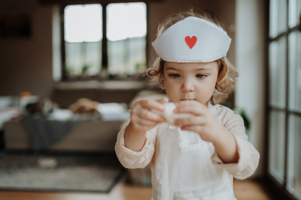 Girl in doctor uniform is playing hospital. Little girl as nurse taking care of imaginary patient