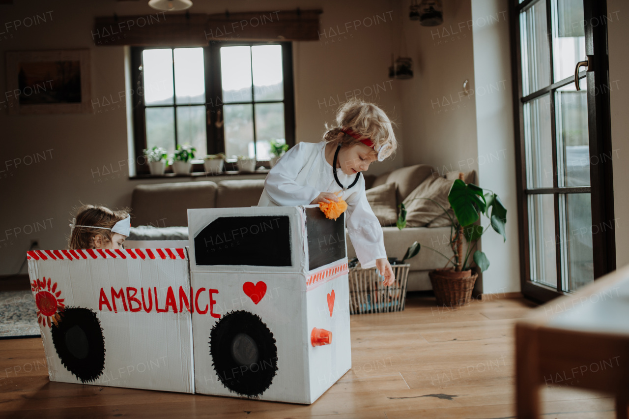 Boy in doctor uniform is playing hospital. Little ambulance paramedic sitting in cardboard ambulance