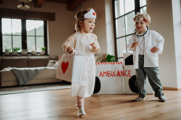 Siblings in doctor uniforms are playing hospital together.