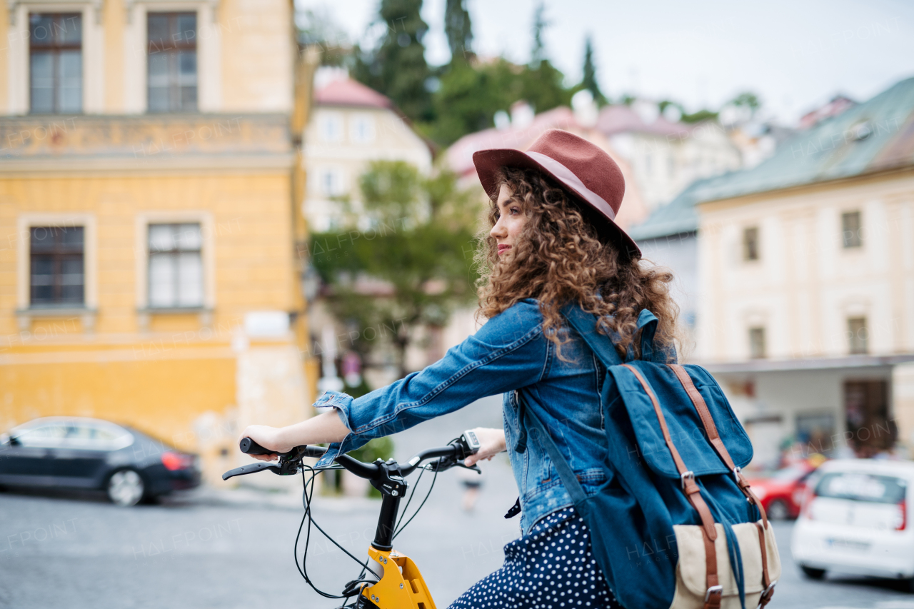 Female traveller on electric scooter in small city, sightseeing. Beautiful tourist using bike during her summer solo trip, vacation.