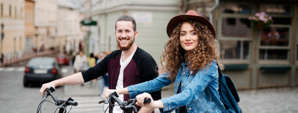 Couple travellers on electric scooters in city, sightseeing. Young tourist using bikes during their summer trip, vacation. Banner with copy space.