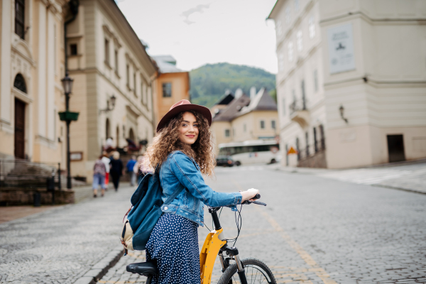 Female traveller on electric scooter in small city, sightseeing. Beautiful tourist using bike during her summer solo trip, vacation.