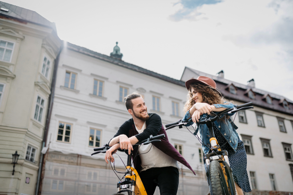 Couple travellers on electric scooters in city, sightseeing. Young tourist using bikes during their summer trip, vacation.