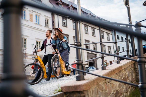 Couple travellers on electric scooters in city, sightseeing. Young tourist using bikes during their summer trip, vacation.