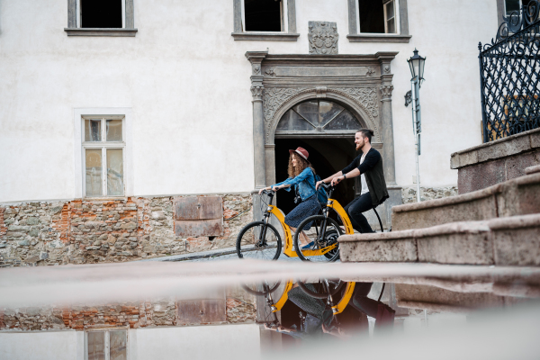 Couple travellers on electric scooters in city, sightseeing. Young tourist using bikes during their summer trip, vacation.