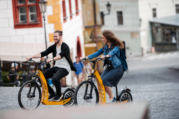 Couple travellers on electric scooters in city, sightseeing. Young tourist using bikes during their summer trip, vacation.