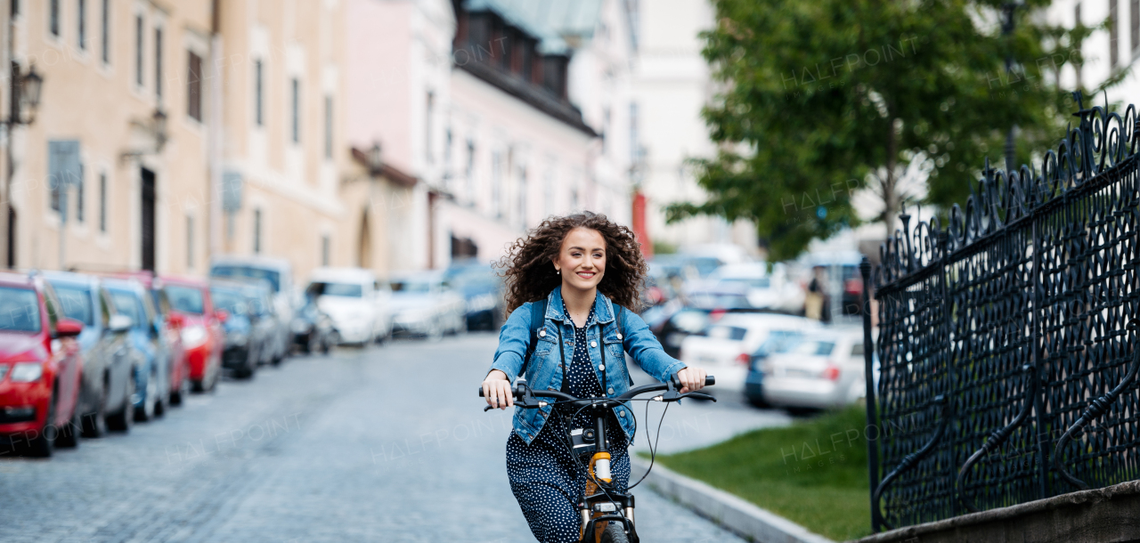 Female traveller on electric scooter in small city, sightseeing. Beautiful tourist using bike during her summer solo trip, vacation. Banner with copy space.