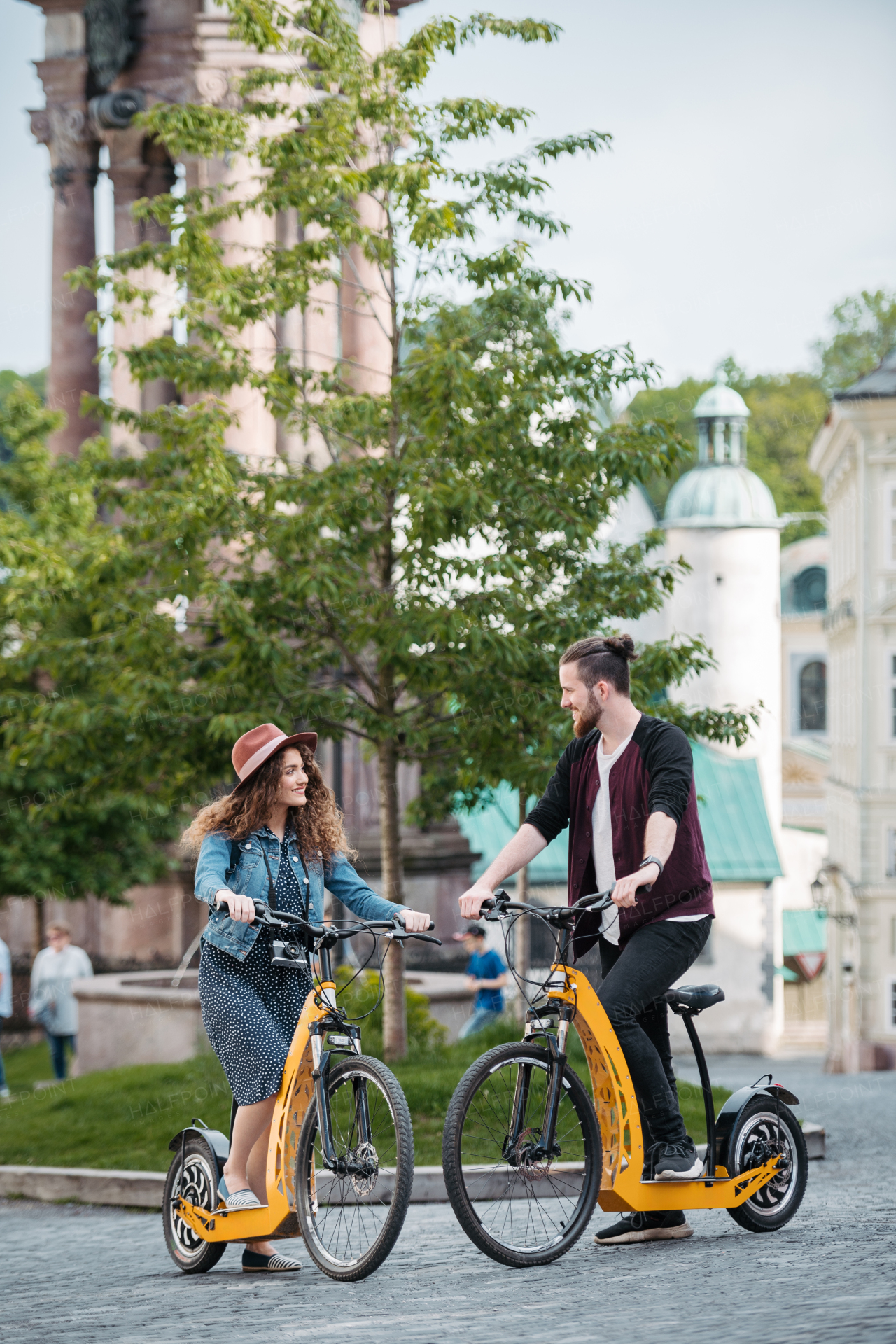 Couple travellers on electric scooters in city, sightseeing. Young tourist using bikes during their summer trip, vacation.