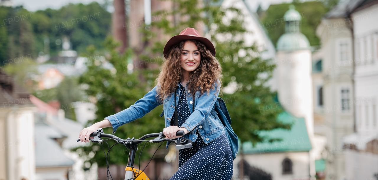 Female traveller on electric scooter in small city, sightseeing. Beautiful tourist using bike during her summer solo trip, vacation. Banner with copyspace.