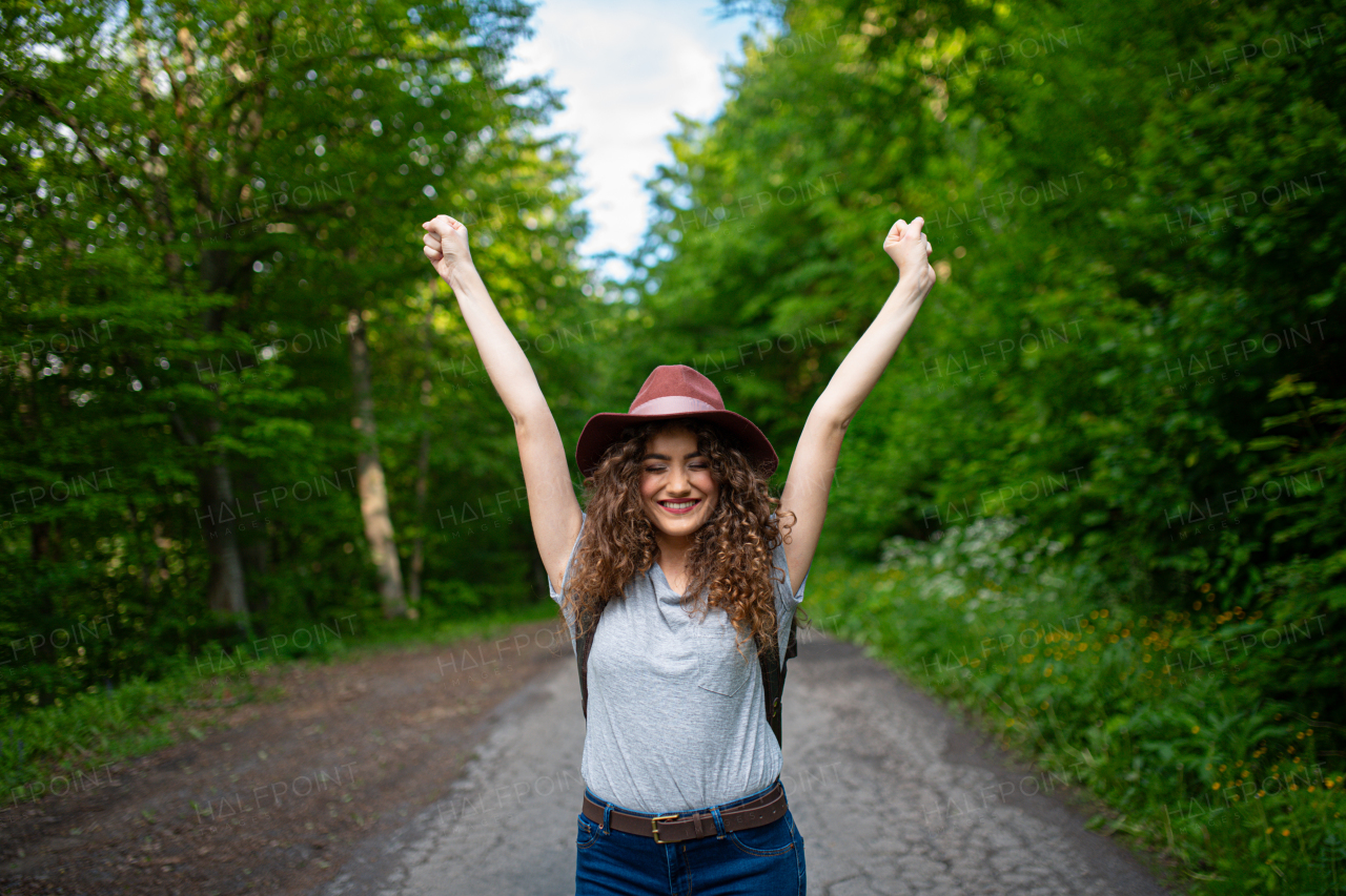 Beautiful young tourist woman traveller with backpack walking in nature. Active female hiker on trail in woods. Solo summer vacation.