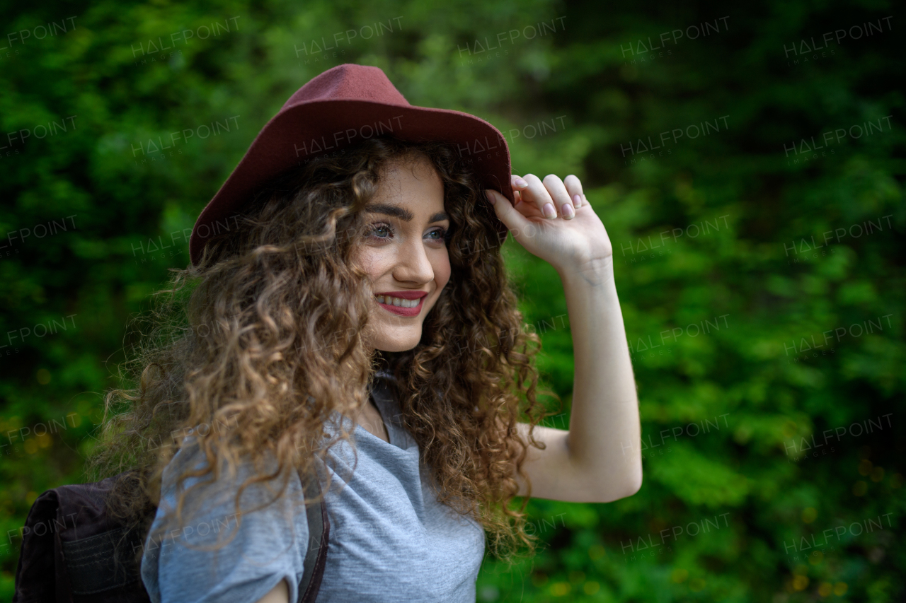 Beautiful young tourist woman traveller with backpack walking in nature. Active female hiker on trail in woods. Solo summer vacation.