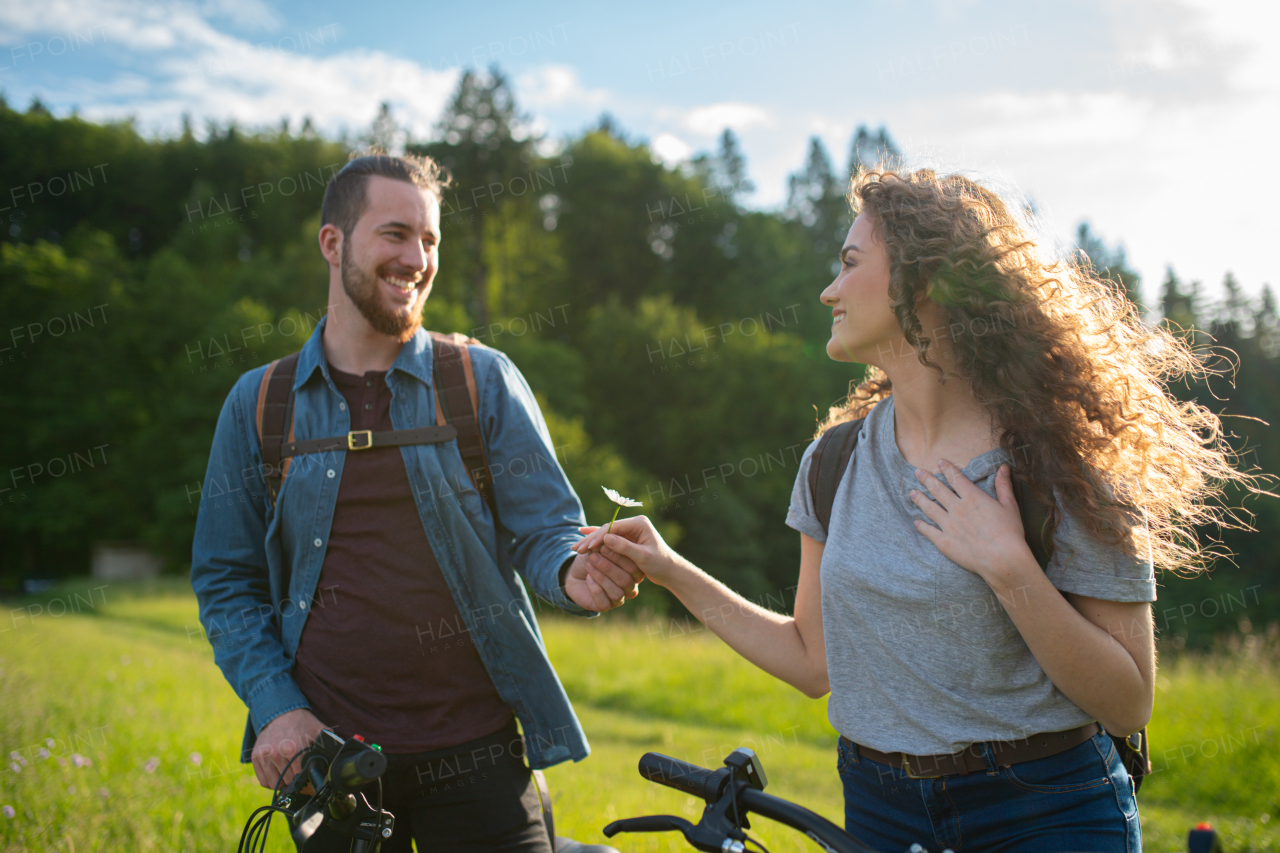 Travellers couple going on e-bike ride in nature. Tourist riding electric bicycles on easy trail road in the middle of forest. Young tourist spending romantic summer vacation oudoors.