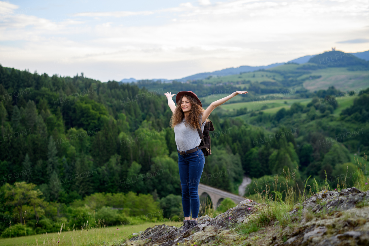 Beautiful young tourist woman traveller with backpack walking in nature. Active hiker on trail in mountain. Solo summer vacation.