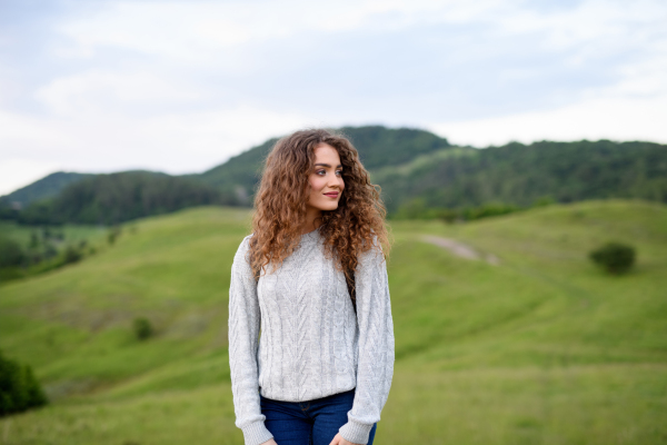 Beautiful young tourist woman traveller with backpack walking in nature. Active hiker on trail in mountains enjoying sunset. Solo summer vacation.