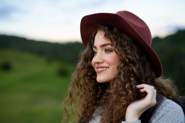 Beautiful young tourist woman traveller with backpack walking in nature. Active hiker on trail in mountains enjoying sunset. Solo summer vacation.