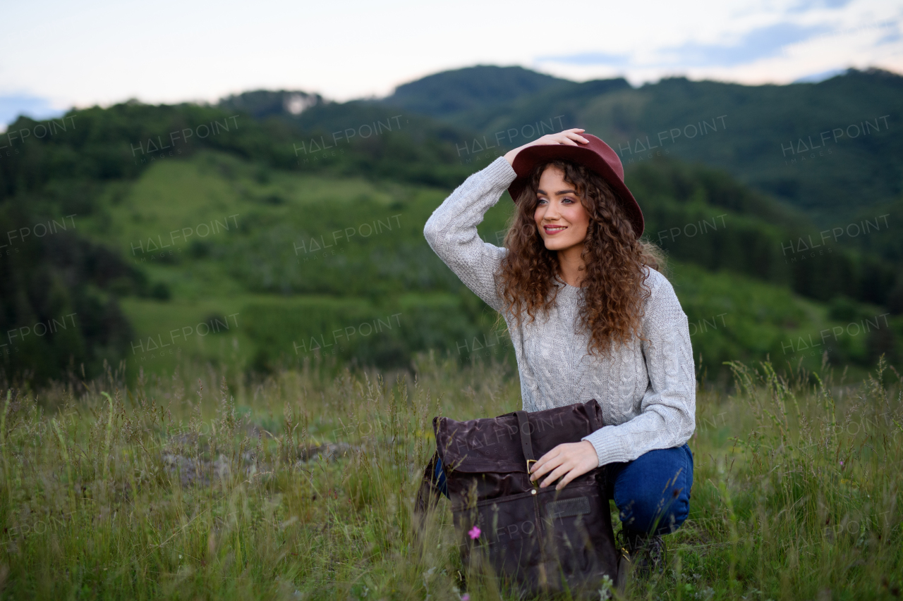 Beautiful young tourist woman traveller with backpack walking in nature. Active hiker on trail in mountains enjoying sunset. Solo summer vacation.