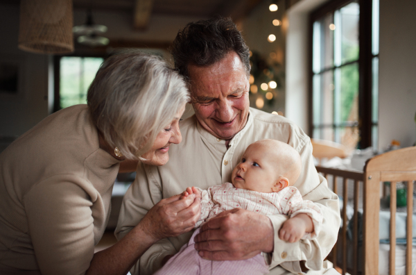 Grandparents holding small baby girl, calming her down, soothing her. Strong bond between grandparents and their grandchild.