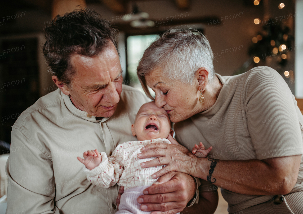 Grandparents holding crying baby girl, calming her down, soothing her. Strong bond between grandparents and their grandchild.