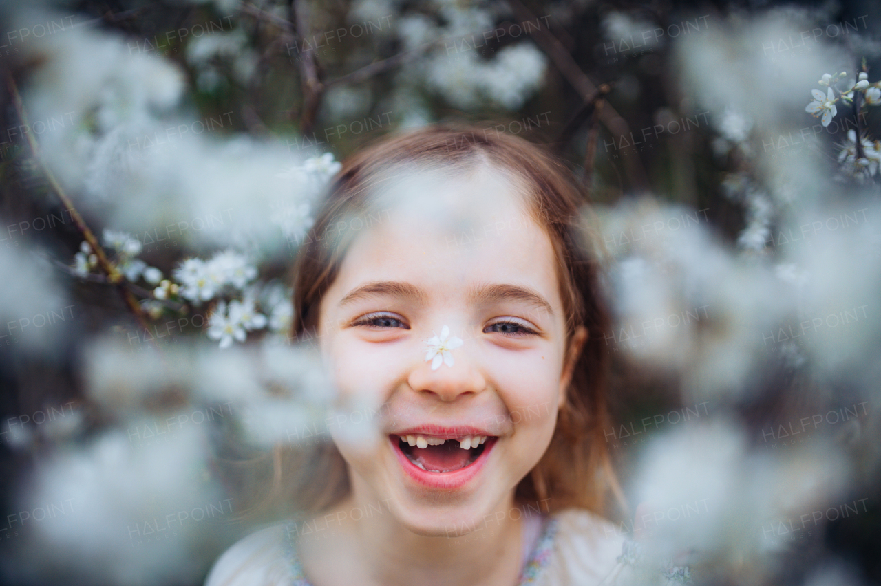 Laughing young girl in the middle of blooming flowers. Concept of springtime in a nature.