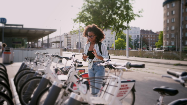 Young university student is renting a city bike through app, using bike-sharing service.