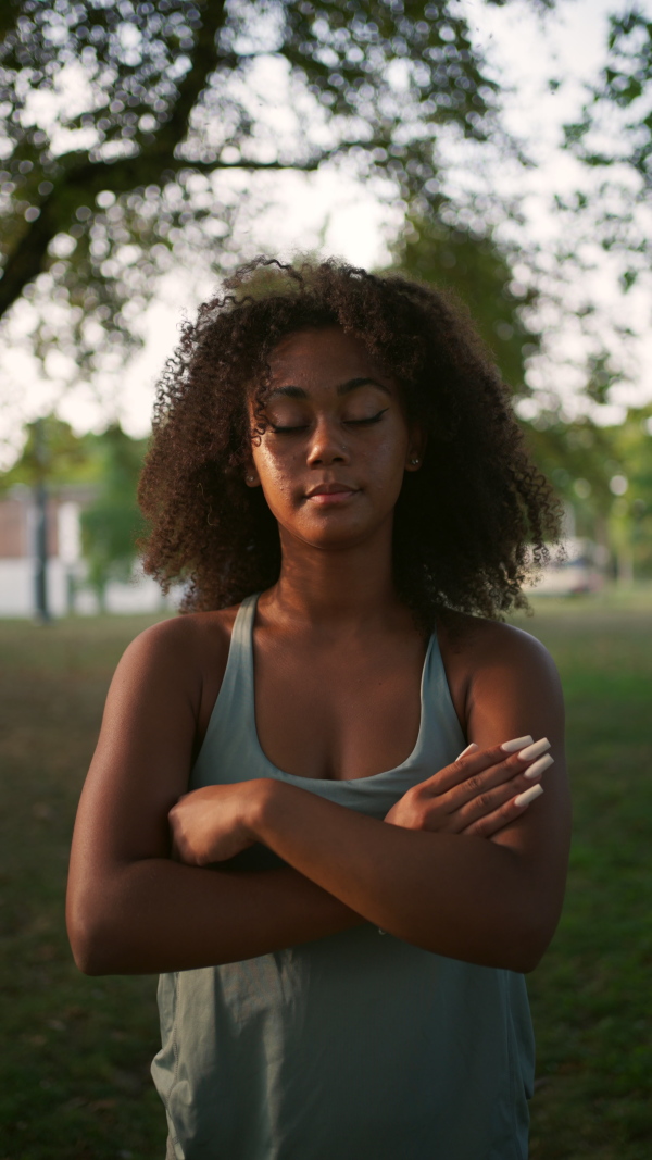 Video of a young sporty woman exercising in city park. Doing yoga outdoors at morning.