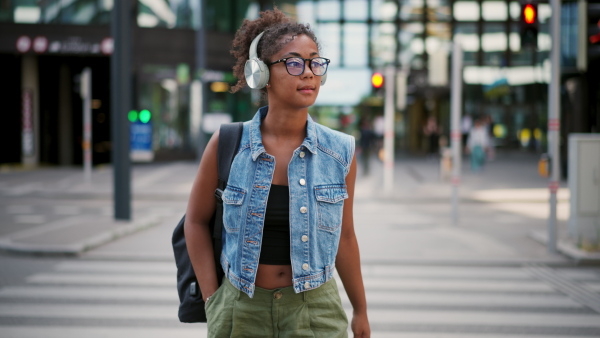 A video of gorgeous young woman with eyeglasses in the city, headphones on head.